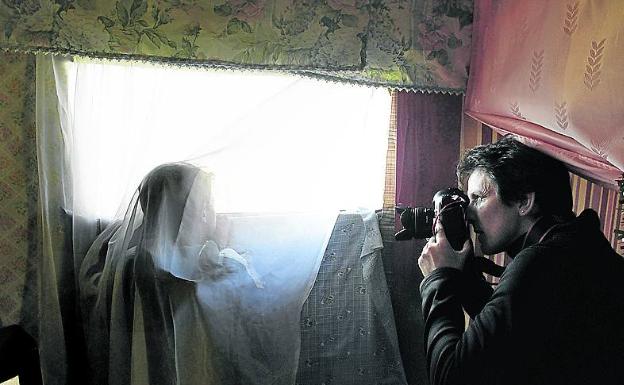 La fotógrafa Susana Vera saca fotos de un niño mirando a través de la ventana de su chabola en el antiguo asentamiento de El Gallinero, a las afueras de Madrid. 