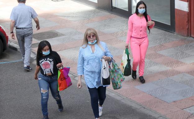 Tres personas pasean por las calles de León con sus mascarillas.