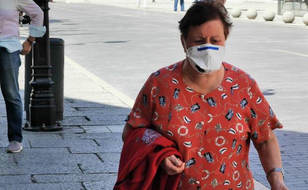 Una mujer con su mascarilla por las calles de León.