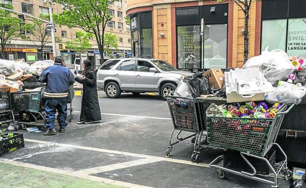 Neoyorquinos buscan comida en los carros con productos caducados que un supermercado ha dejado en la calle, durante la crisis del coronavirus.