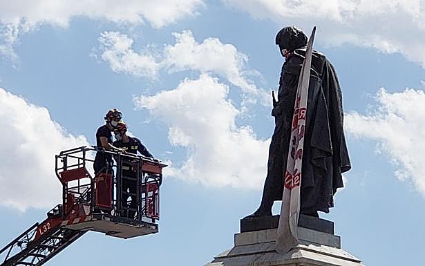 Galería. Bomberos de León situando la bandera de la Cultural en la estatua de Guzmán.