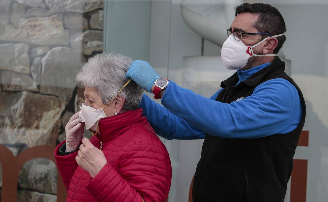 Un hombre ayuda a una mujer a colocarse bien la mascarilla.