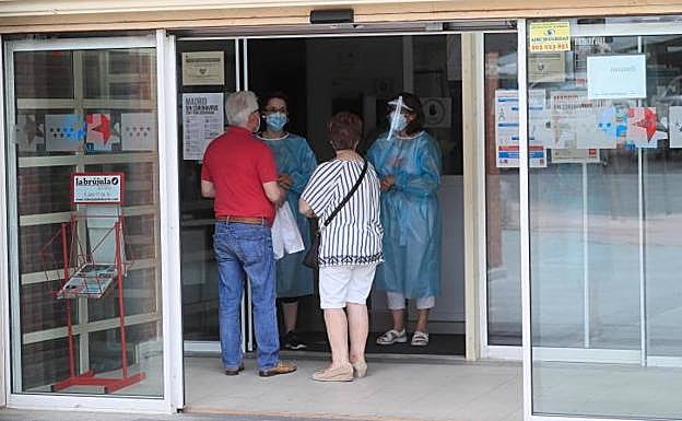 Dos sanitarios niegan la entrada a un centro de Salud en Madrid cerrado por un brote.