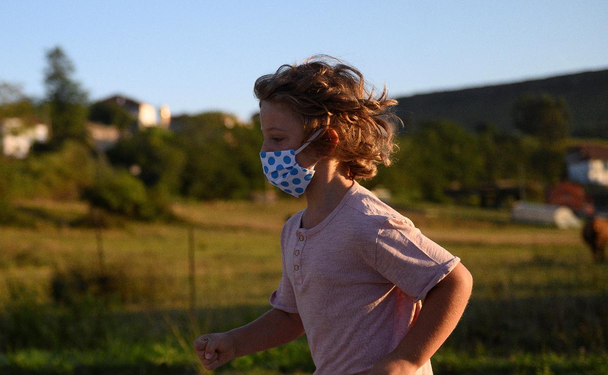 Un niños corre con mascarillas. 
