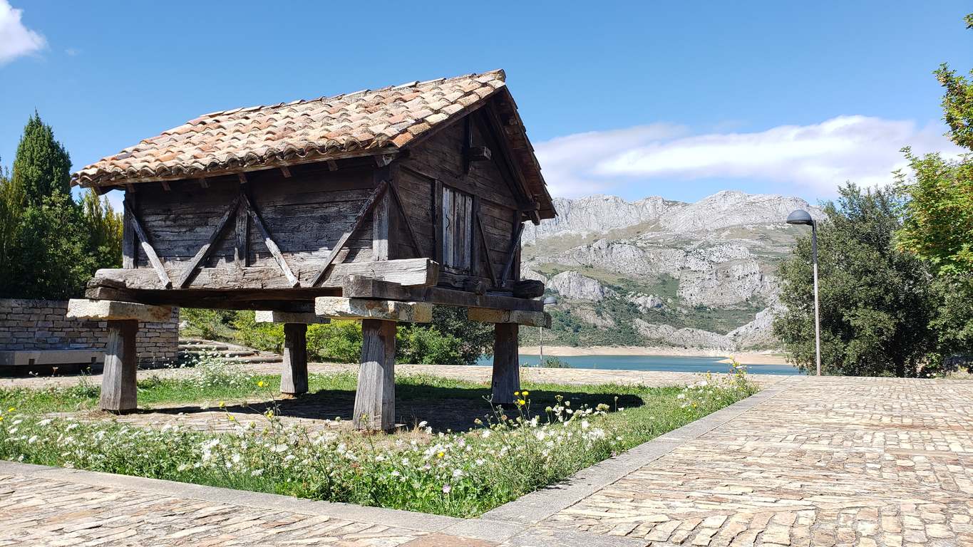 Ubicado junto a la Ermita de Nuestra Señora, en Riaño, el banco ofrece unas privilegiadas vistas sobre el pantano y Picos | El entorno, con las viejas campanas y un 'horreo leonés', completa un escenario idílico. 