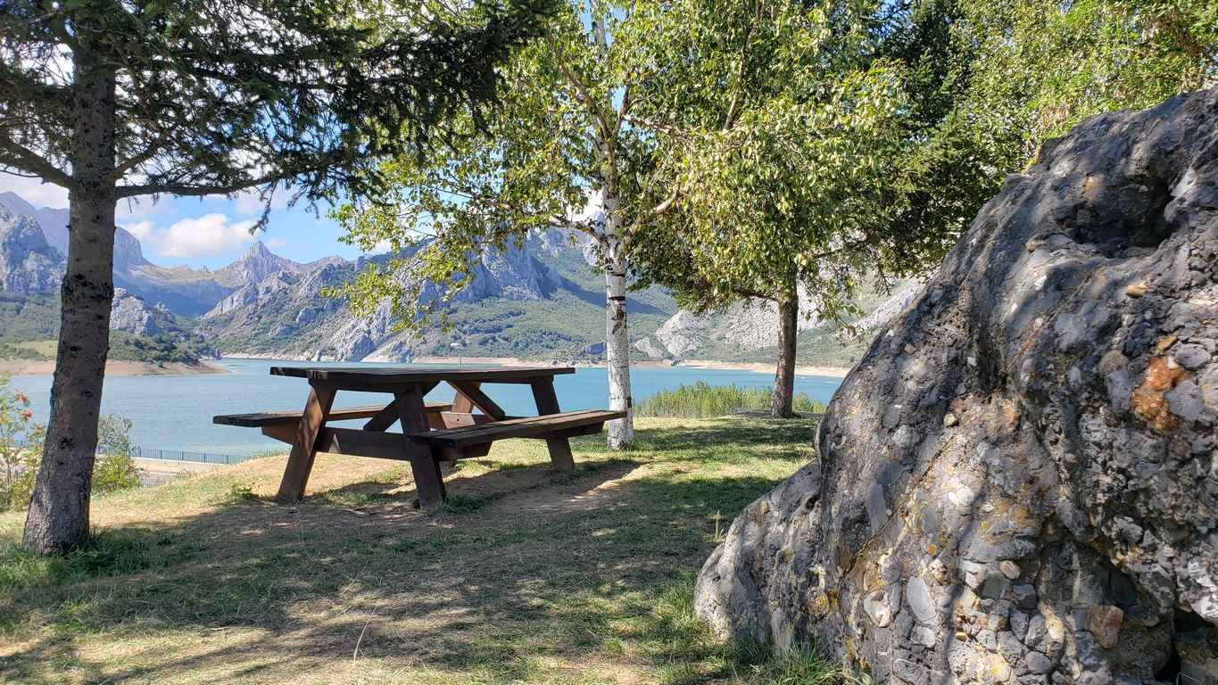 Ubicado junto a la Ermita de Nuestra Señora, en Riaño, el banco ofrece unas privilegiadas vistas sobre el pantano y Picos | El entorno, con las viejas campanas y un 'horreo leonés', completa un escenario idílico. 