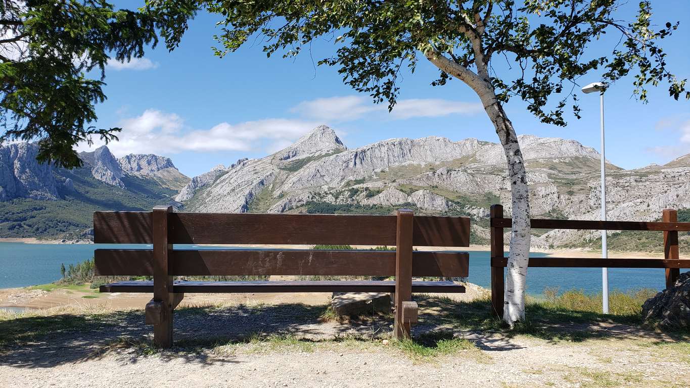 Ubicado junto a la Ermita de Nuestra Señora, en Riaño, el banco ofrece unas privilegiadas vistas sobre el pantano y Picos | El entorno, con las viejas campanas y un 'horreo leonés', completa un escenario idílico. 