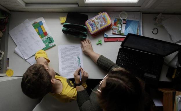 Un niño estudia junto a un adulto. 