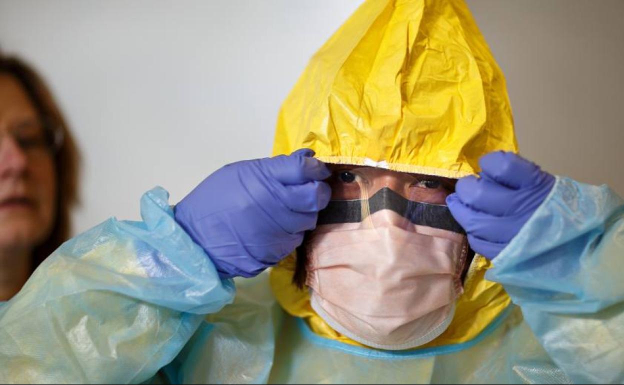 Un médico se enfunda un EPI. 