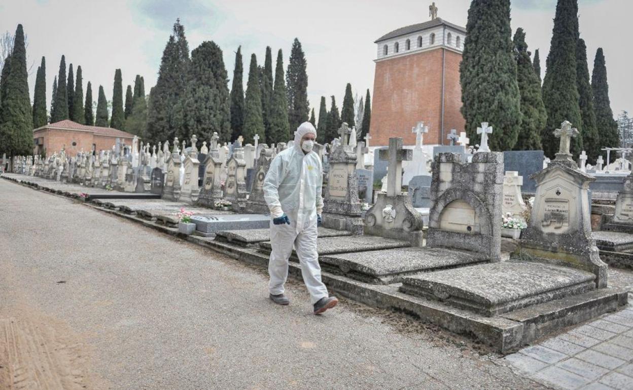 Un operario, equipado con un EPI, en un cementerio municipal.