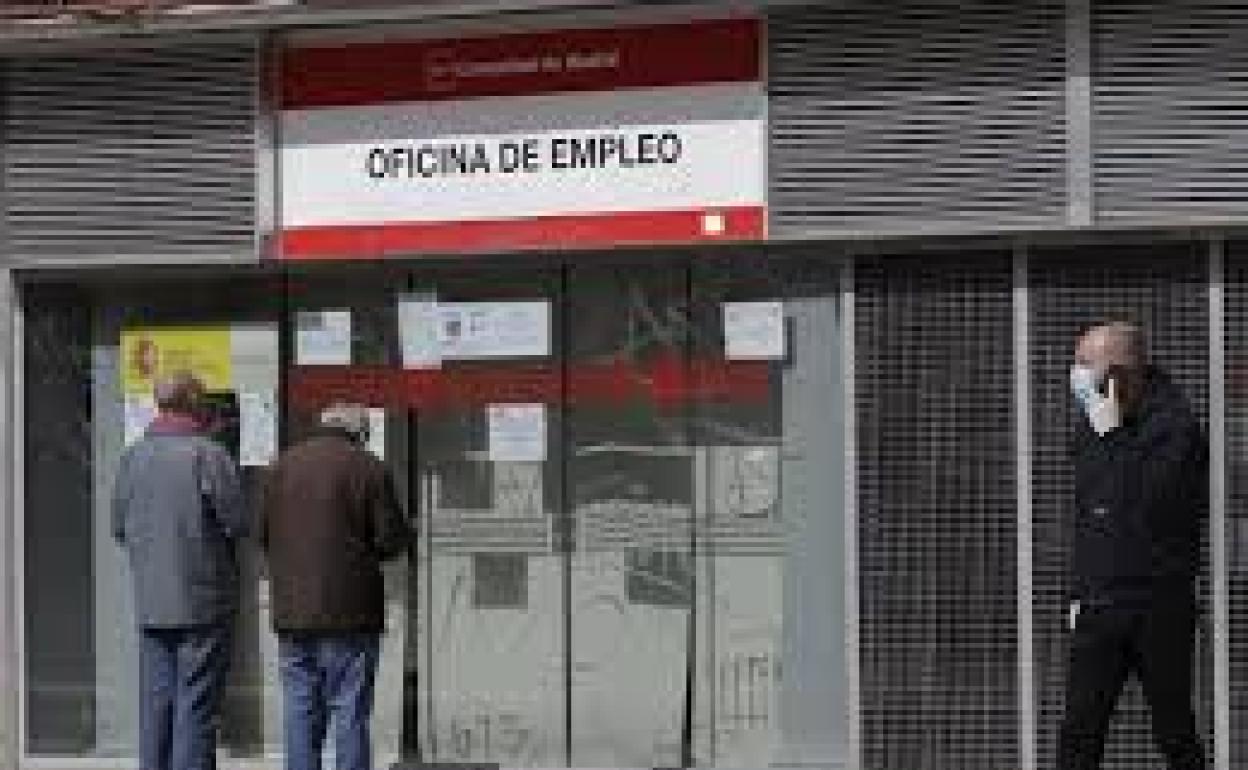Dos hombres leen los carteles de una oficina de empleo cerrada,en Alcorcón 
