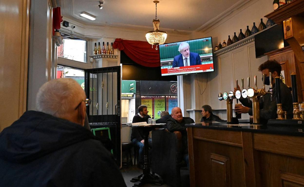 Clientes de un bar de Reino Unido siguen la intervención de Johnson. 