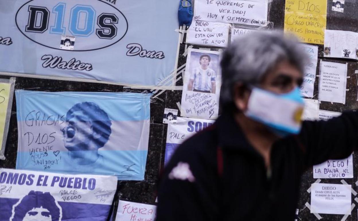 Un hombre espera junto a una pared con banderas e imágenes del exfutbolista argentino Diego Armando Maradona. 