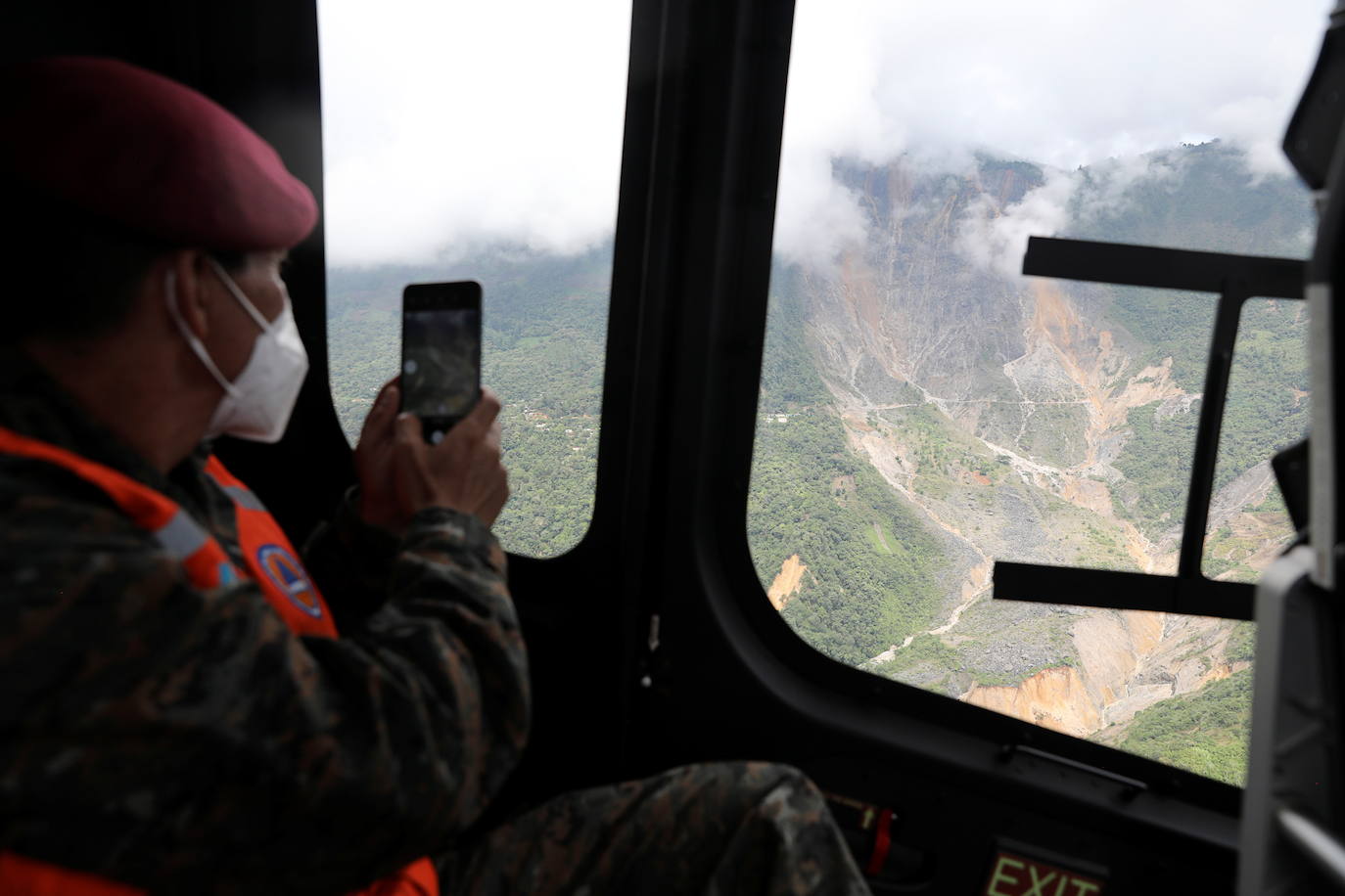 Un soldado graba con su teléfono durante un sobrevuelo en un área golpeada por un deslizamiento de tierra, provocado por las fuertes lluvias traídas por la tormenta Eta, mientras continúa la búsqueda de víctimas en el pueblo enterrado de Queja.