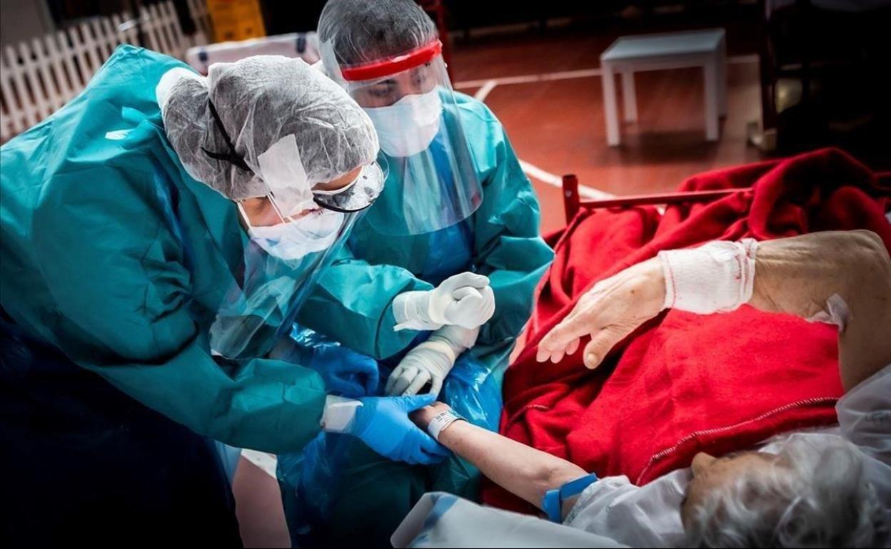 Dos sanitarias atienden a un paciente covid. 