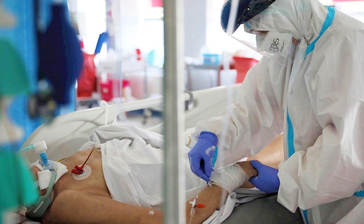 Imagen de un sanitario atendiendo a un paciente covid en una UCI.