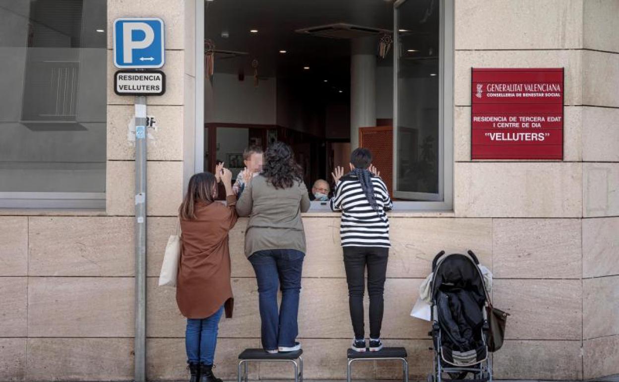 Una anciana recibe la visita de sus nietas a través de una ventana de la residencia de Velluters de València para evitar contagios de coronaviurs 