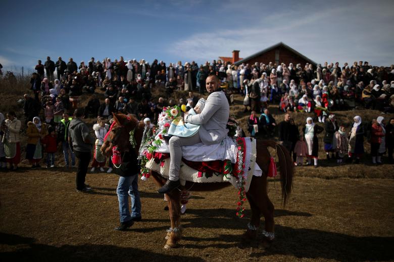 Bulgaria | Un musulmán lleva a su hijo a caballo mientras asisten a un ritual antes de una ceremonia de circuncisión masiva en el pueblo de Ribnovo.
