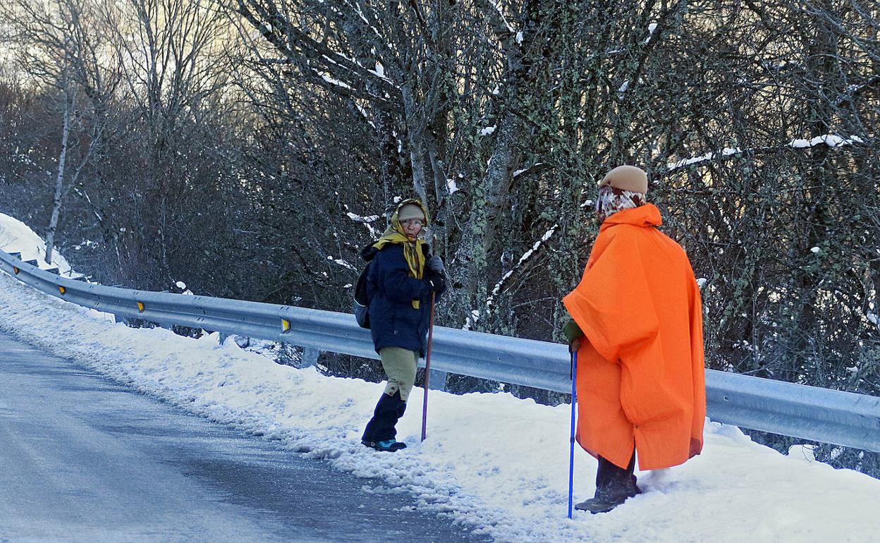 Dos peregrinos hablan en una carretera nevada. 