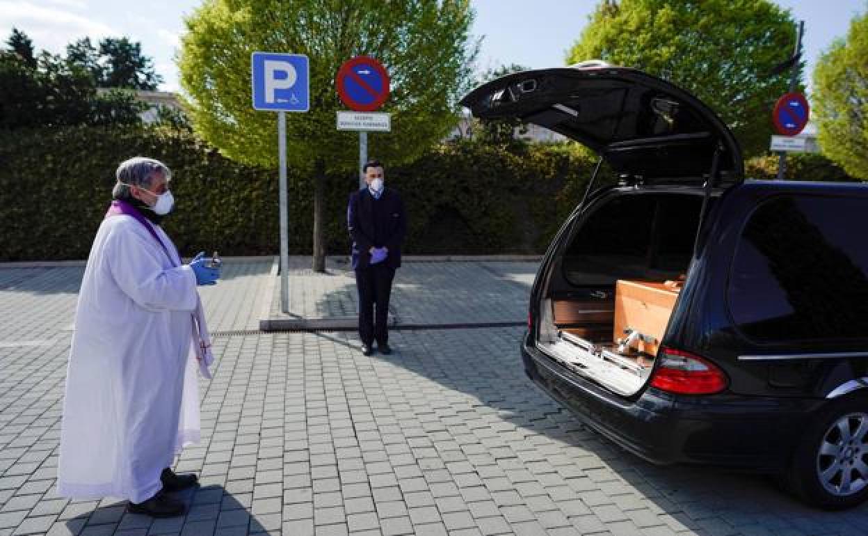 Un sacerdote acompaña los restos mortales de una víctima de la covid. 