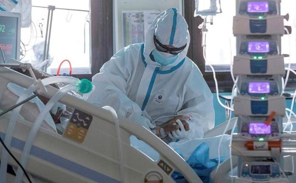 Un sanitario comprueba el estado de un paciente en la UCI. 