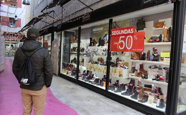 Imagen principal - Los leoneses pasan frente a los escaparates del centro de León con las 'segundas rebajas'.