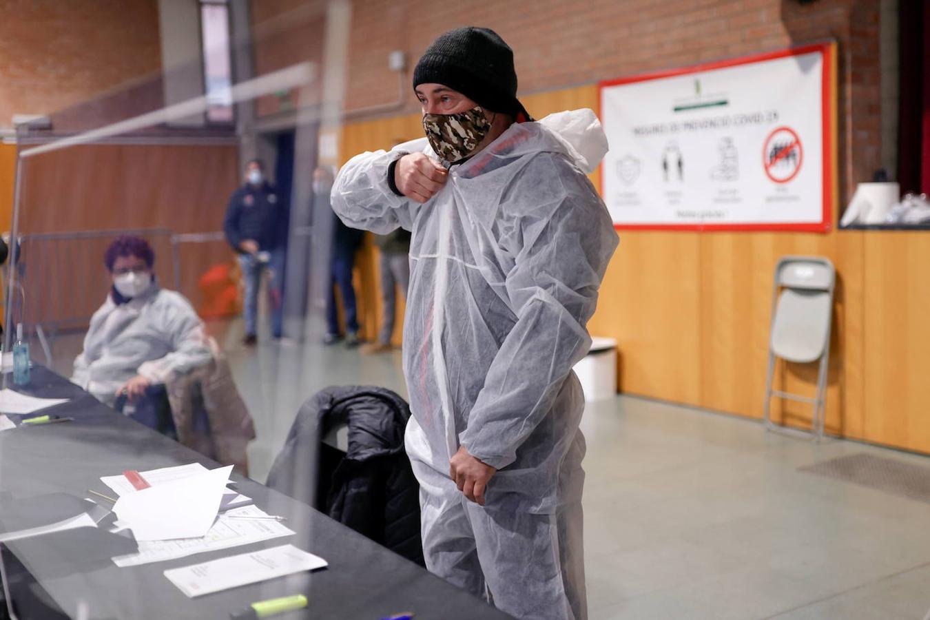 Un miembro de una mesa electoral se pone un traje de protección para recibir a los votantes.