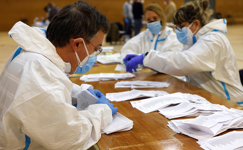 Varias personas vestidas con equipos de protección individual (EPI) realizan el recuento de votos en las mesas electorales del Polideportivo Municipal de la España Industrial de Barcelona.