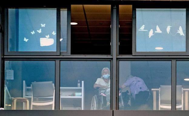 Una mujer en la ventana de una residencia de ancianos. 