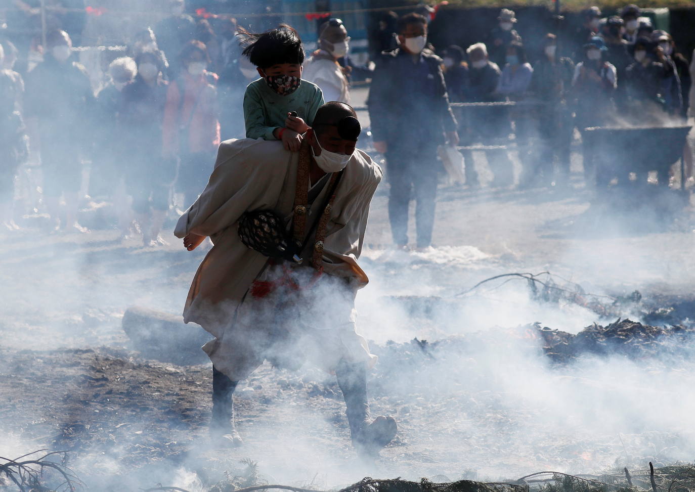 Los fieles siguieron a los monjes, con máscaras debido al coronavirus. Algunos monjes llevaban a los niños pequeños sobre las brasas mientras un humo oscuro se elevaba en el aire.