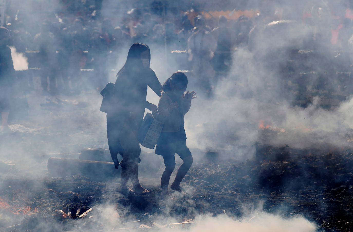 Una mujer y una niña caminan sobre brasas.