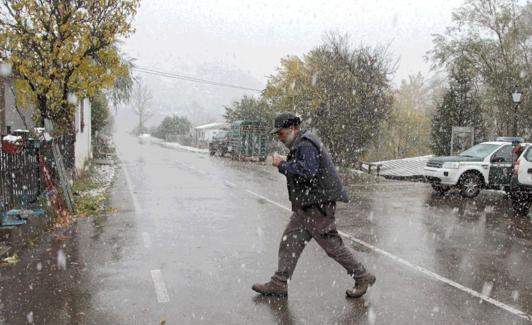 Un hombre camina bajo la nieve en una localidad de la montaña leonesa. 