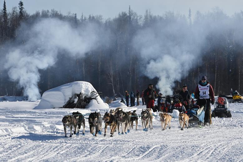 Ryne Olson conduce a su equipo de perros pasando por fogatas en el río Susitna durante la carrera 