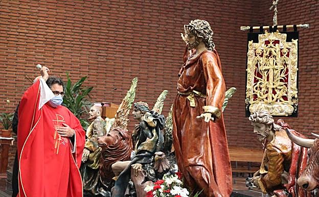 El párroco derrama agua bendita sobre la imagen del titular de la Cofradía del Cristo del Gran Poder.