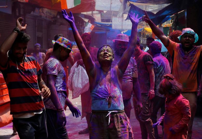 La gente baila mientras se arrojan polvos de colores durante las celebraciones de Holi en Calcuta, India.