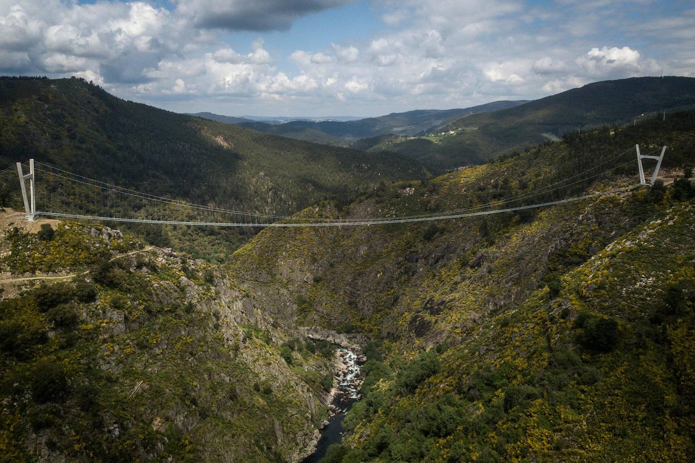 Portugal inauguró este jueves 29 de abril el puente peatonal suspendido más largo del mundo, a 175 metros sobre el río Paiva, en el norte, y que con sus 516 metros supera el récord establecido en 2017 por la pasarela Charles Kuonen de los Alpes suizos. El puente atraviesa un barranco granítico del municipio de Arouca y está formado por 127 planchas de rejilla con barandillas metálicas de 1,20 metros de ancho, sujetas por cables de acero a unos pilares en forma de 'V' situados a cada extremo.