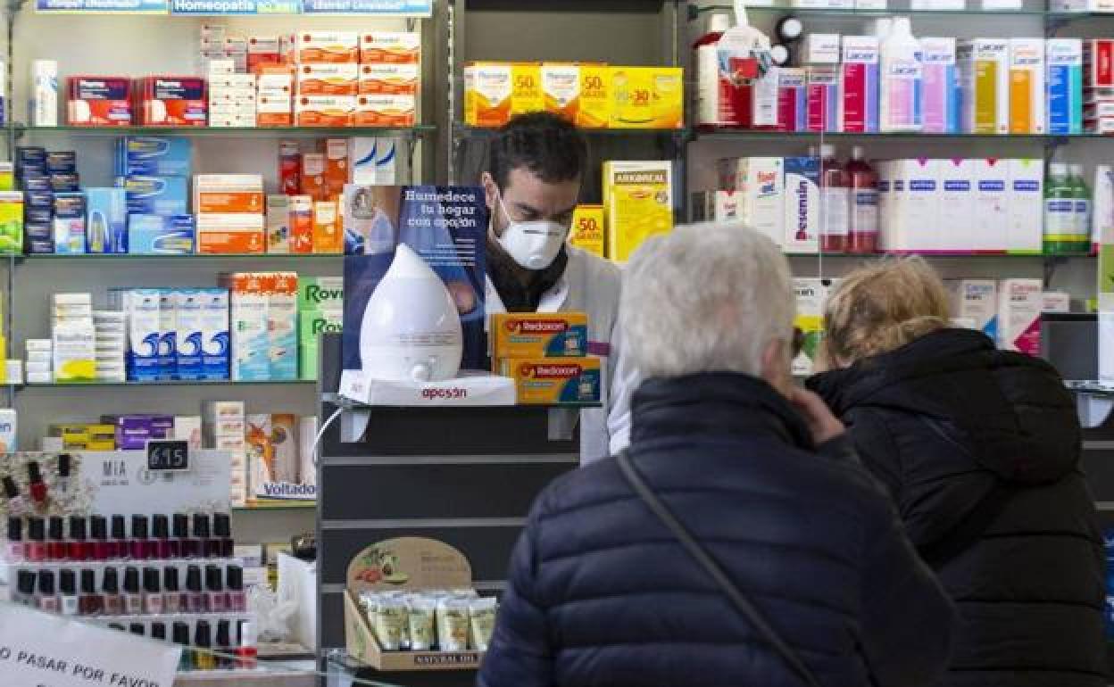 Un farmacéutico atiende a dos clientas.