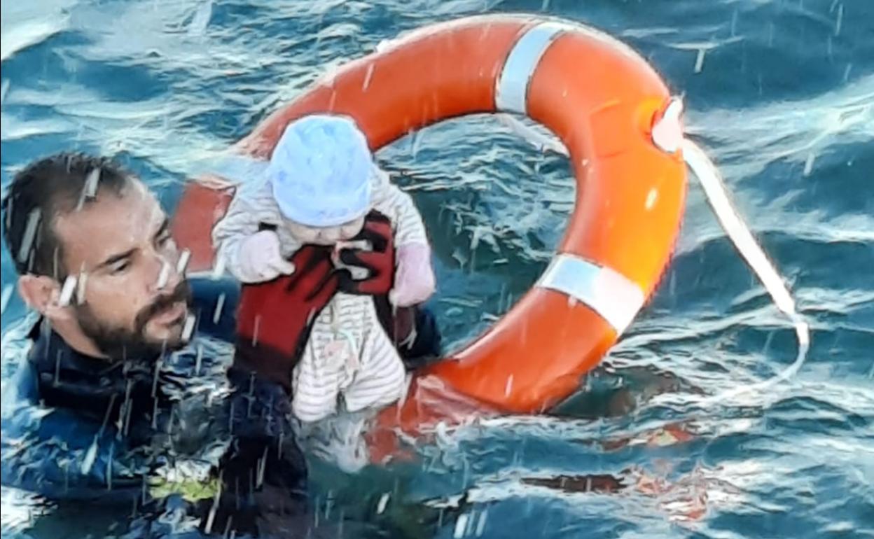 El buzo de la Guardia Civil Juan Francisco Valle sostiene a un bebé este martes en la playa del Tarajal, Ceuta.