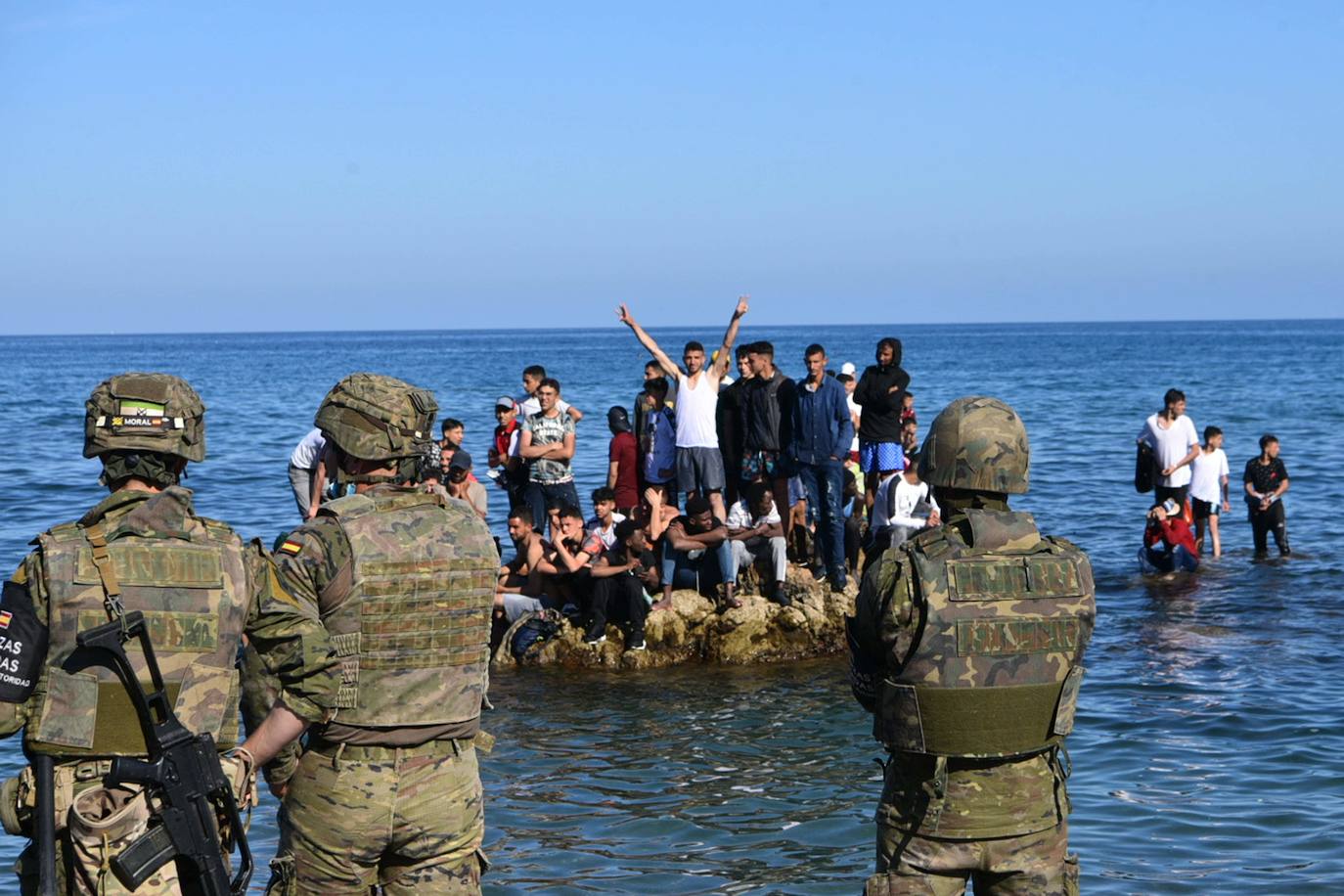 Inmigrantes llegados a Ceuta ante la mirada de las fuerzas de seguridad.