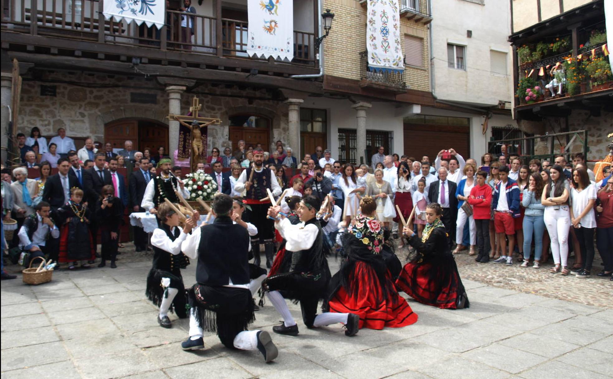 Paleos típicos ante la imagen del Cristo en la Plaza engalanada con estandartes pintados con motivos del bordado serrano.