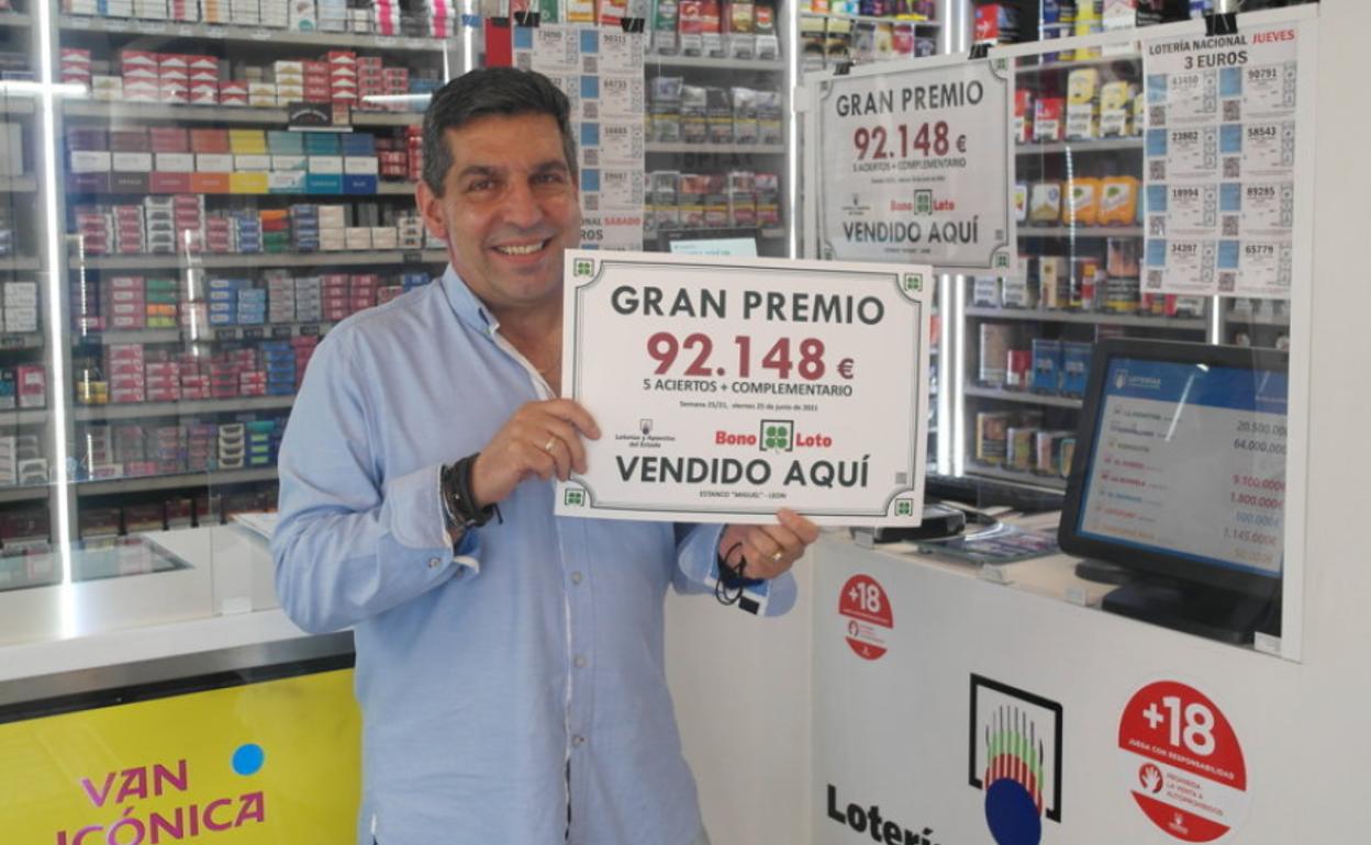 El regente del estanco donde se vendió el boleto agraciado posa con el cartel del premio repartido.