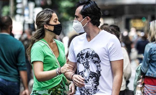 Una pareja pasea con mascarilla. 