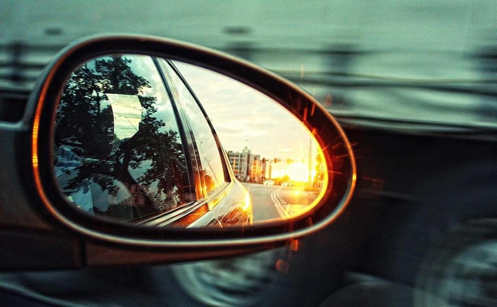 Una ciudad queda atrás en el retrovisor de un coche. 