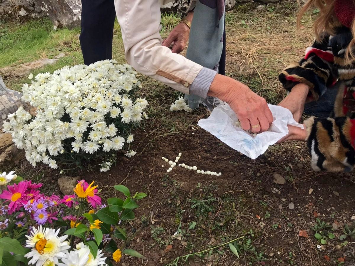 Un grupo de personas adornan las sepulturas en un pueblo de la montaña leonesa antes de la festividad de Todos los Santos.