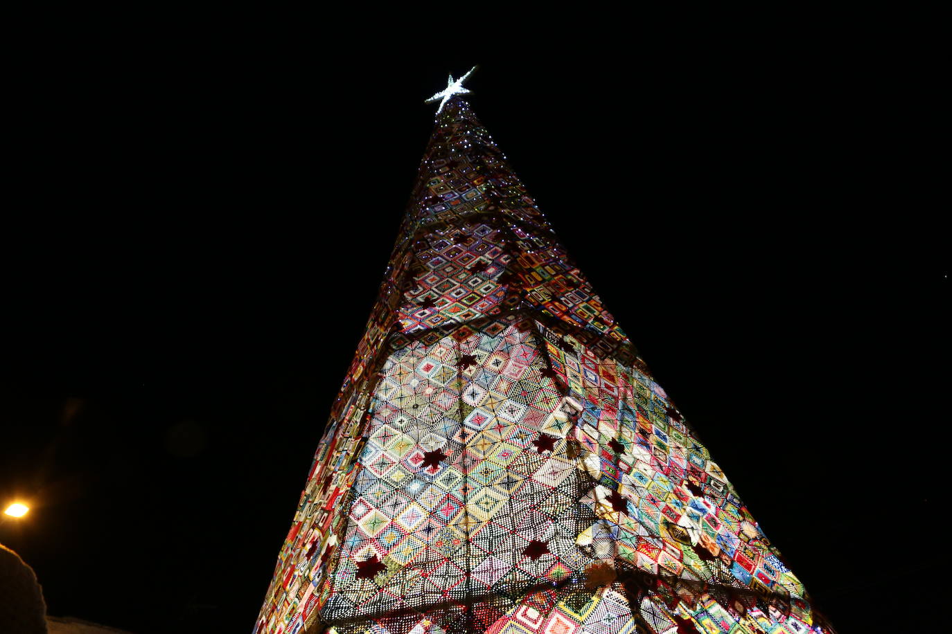 La localidad leonesa enciende su famoso árbol de Navidad realizado a ganchillo por las vecinas del pueblo.