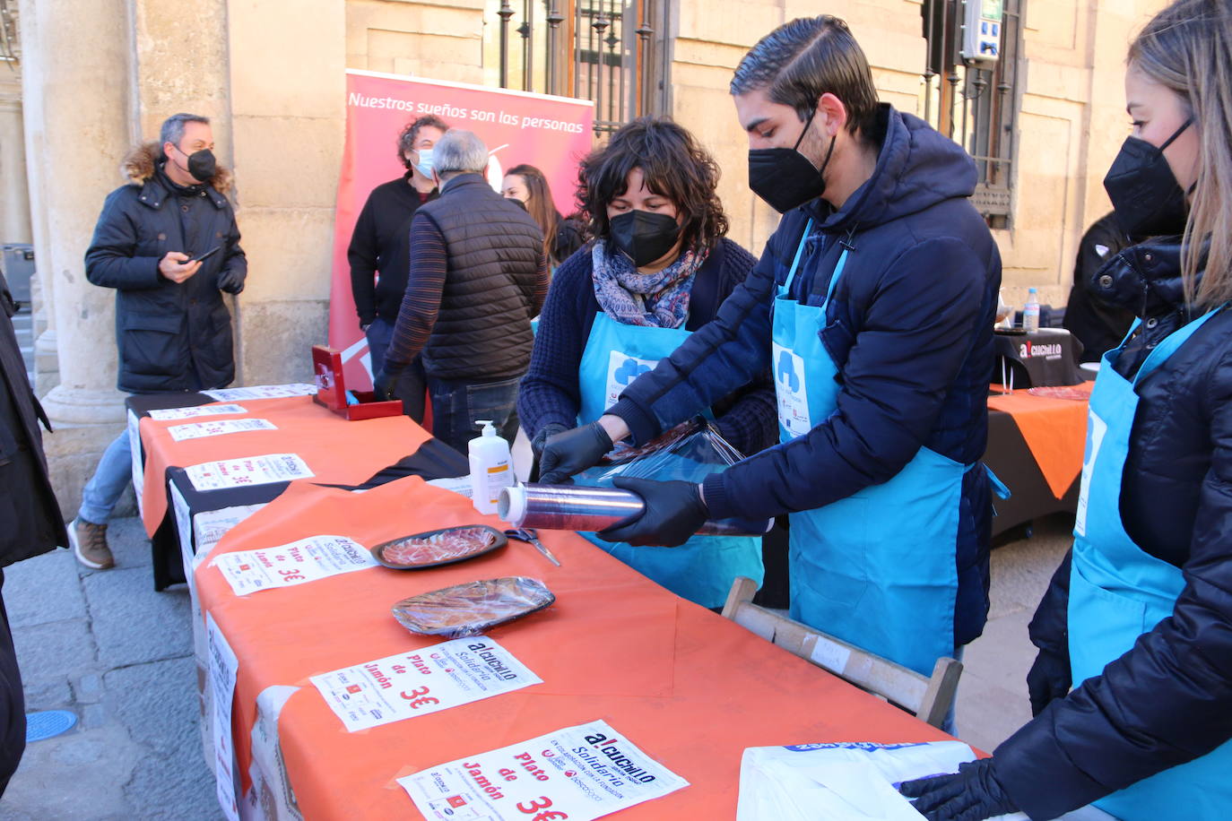 Centenares de personas participan en el corte de platos de jamón por una acción benéfica.