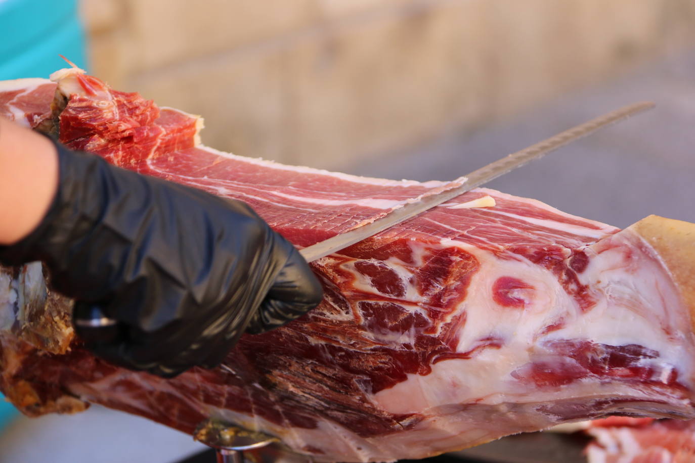 Centenares de personas participan en el corte de platos de jamón por una acción benéfica.