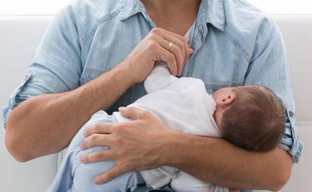 Un hombre sostiene a un bebé recién nacido.