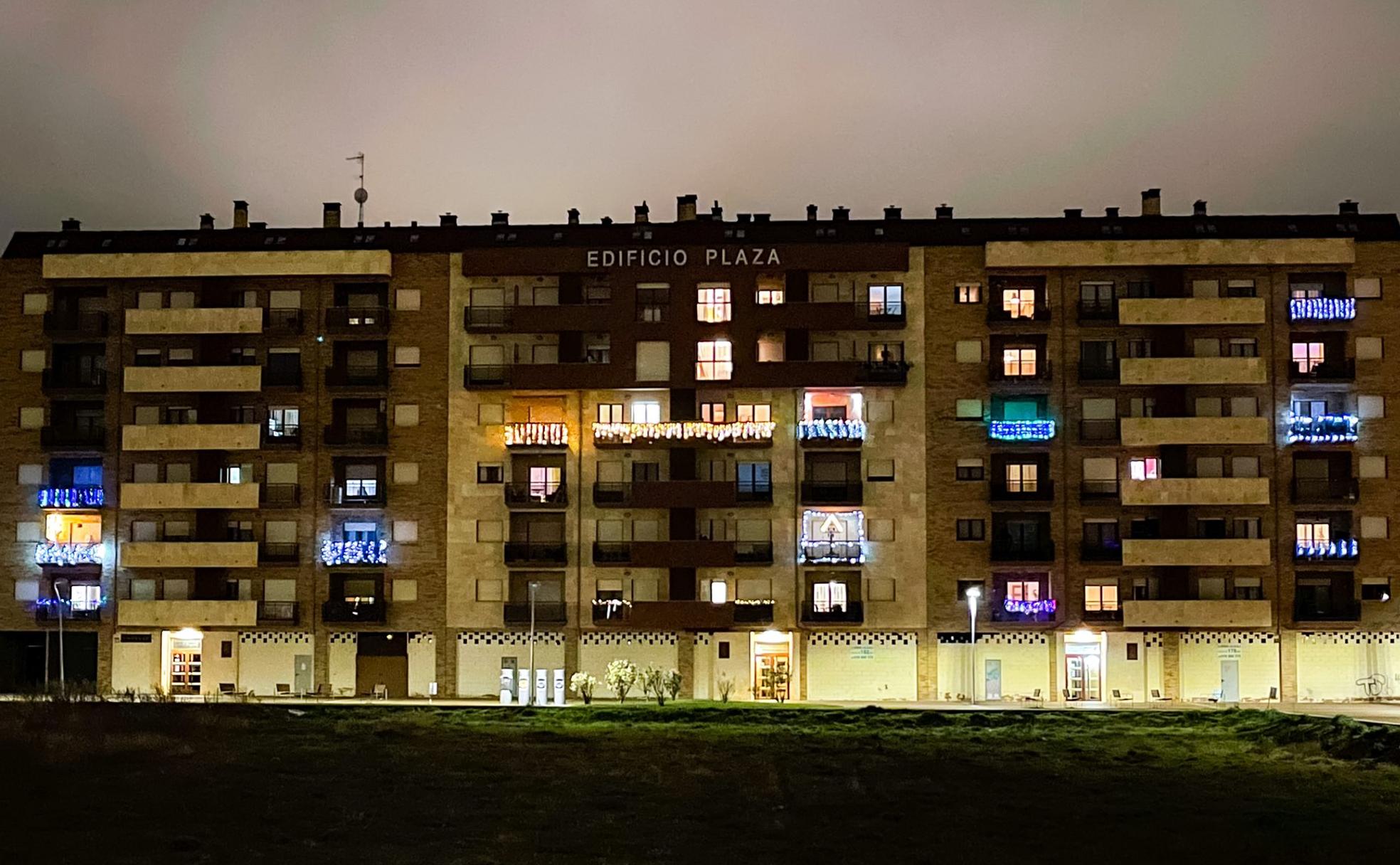 Uno de los bloques del barrio de La Lastra con varios de sus balcones iluminados para celebrar la Navidad y ante la falta de decoración instalada en sus calles.