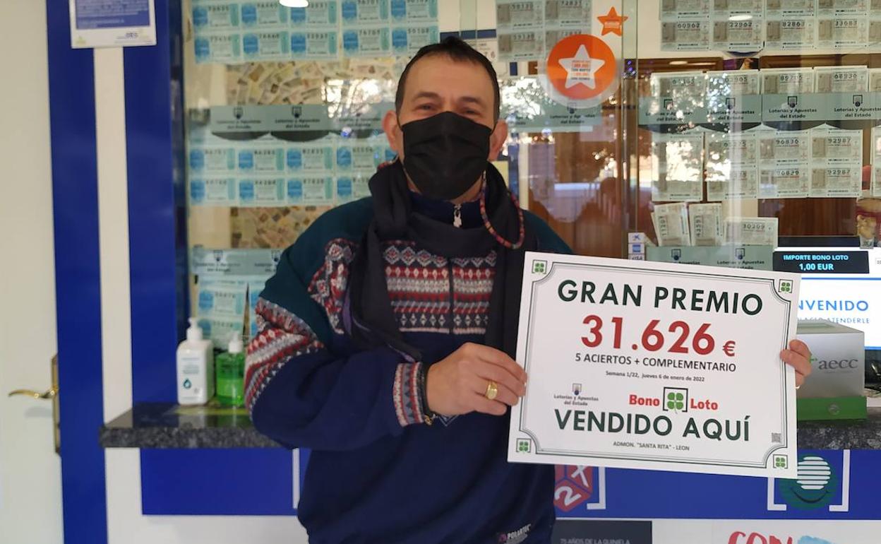 El propietario de la administración posa con el cartel del premio. 